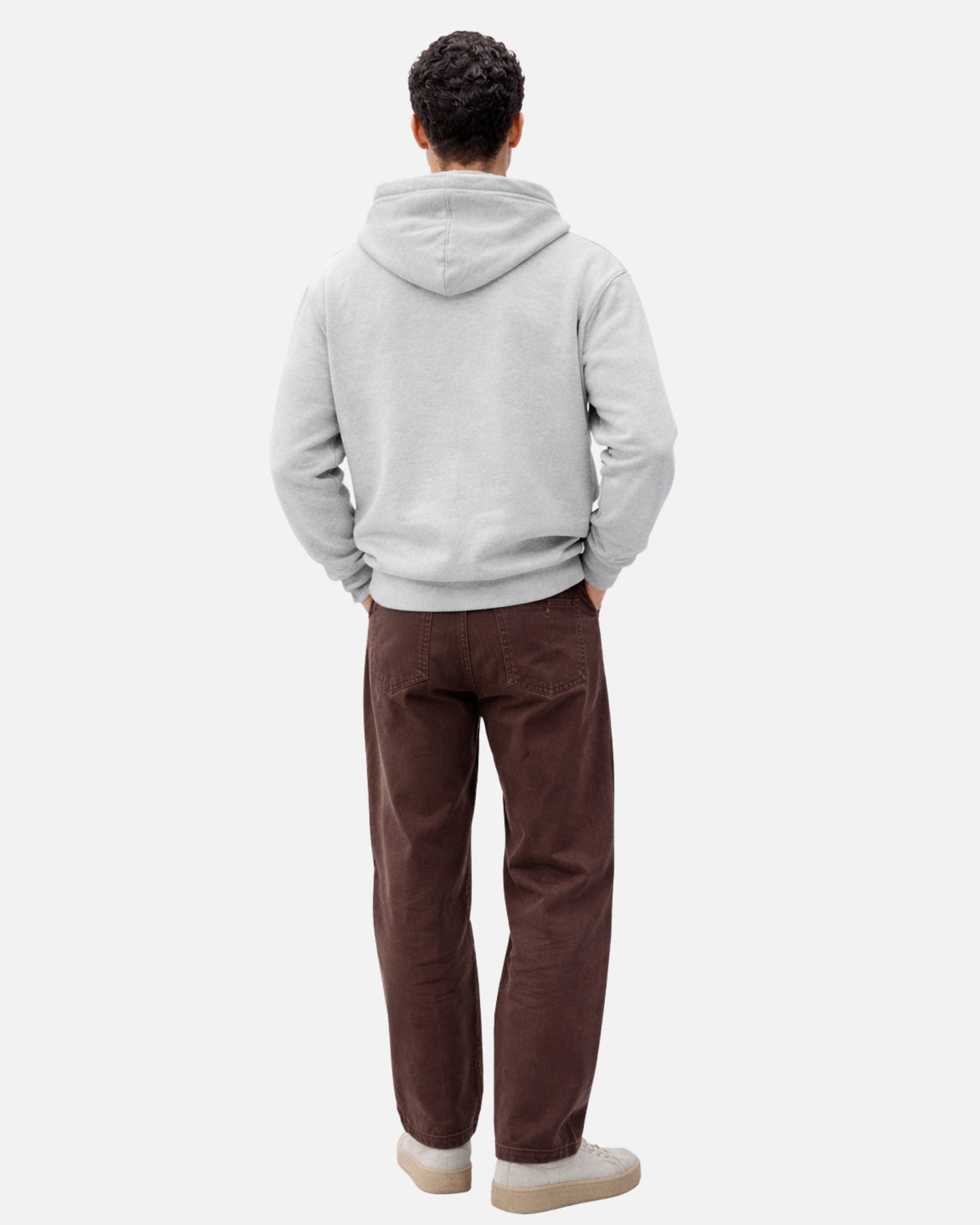 Person wearing a gray hoodie and brown pants on a white background