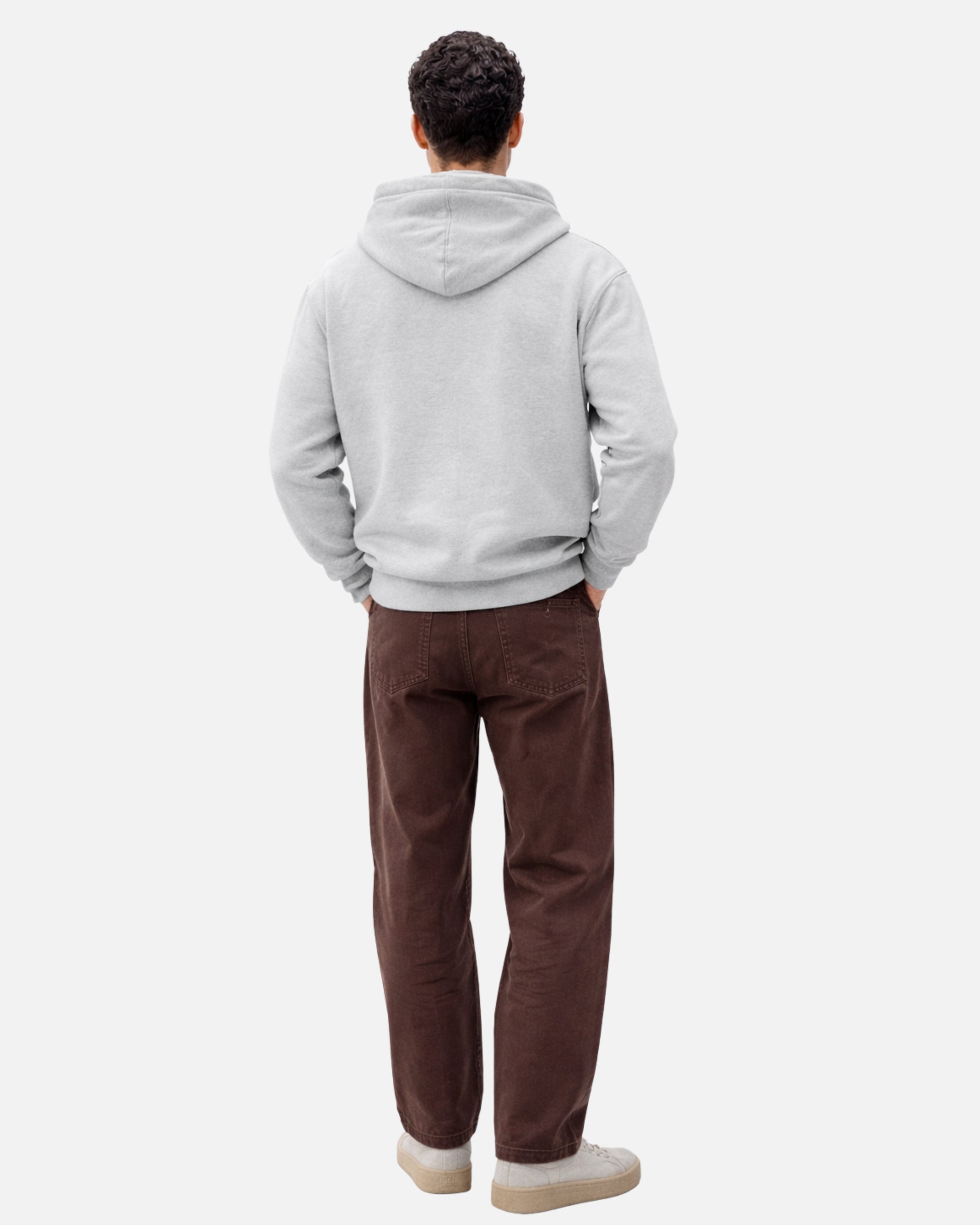 Person wearing a gray hoodie and brown pants on a white background