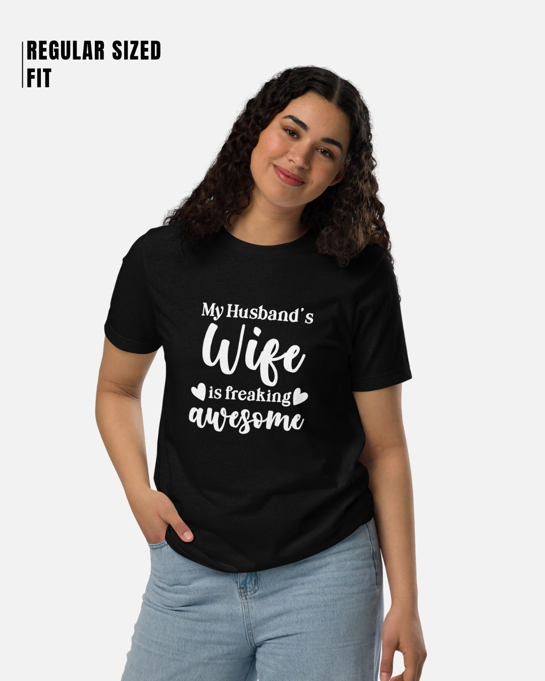 Woman wearing a black t-shirt with 'My Husband's Wife is freaking awesome' text on a white background